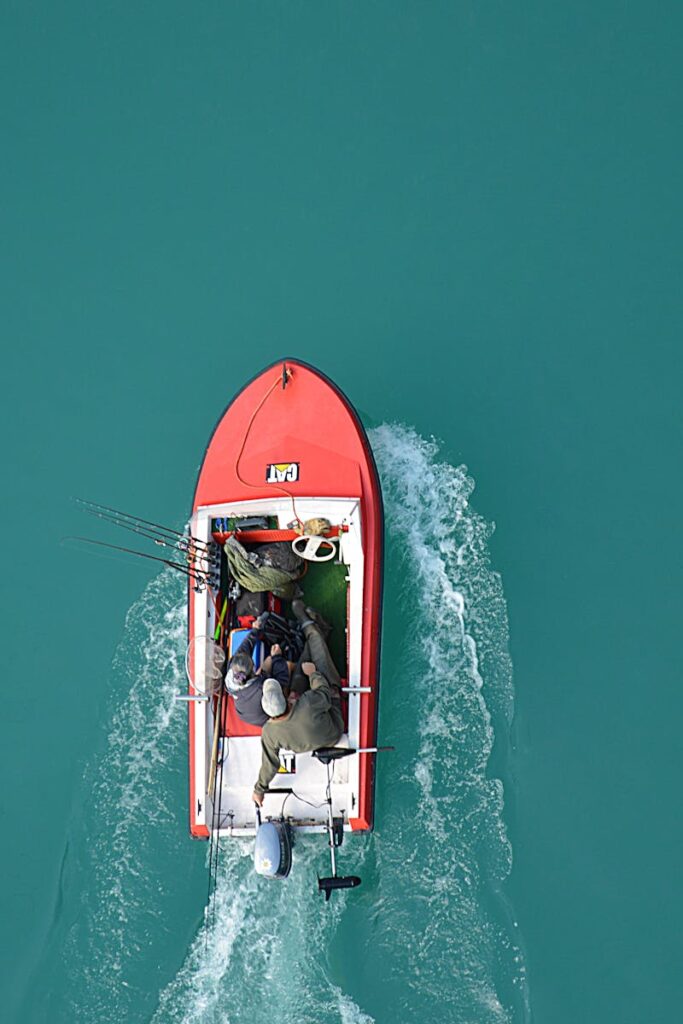 pexels-photo-240561-240561 Top view of a red motorboat with fishermen navigating open turquoise waters.